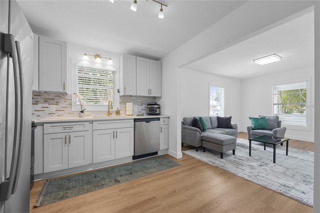 kitchen featuring light wood-style flooring, a sink, light countertops, appliances with stainless steel finishes, and open floor plan