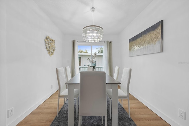 dining room with light wood finished floors, a notable chandelier, and baseboards