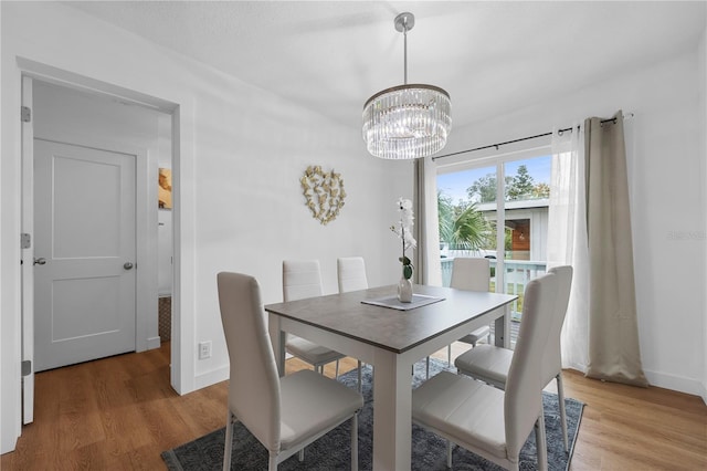 dining area featuring baseboards, a notable chandelier, and wood finished floors