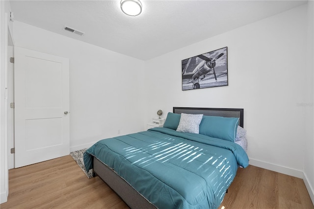 bedroom featuring visible vents, baseboards, and wood finished floors