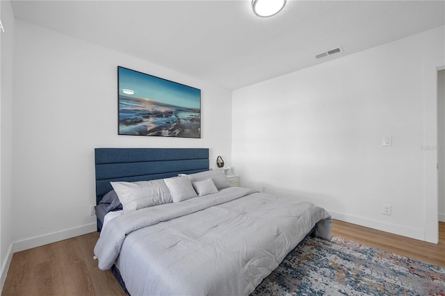 bedroom featuring visible vents, baseboards, and wood finished floors