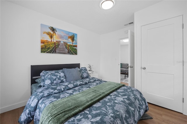 bedroom featuring wood finished floors, visible vents, and baseboards