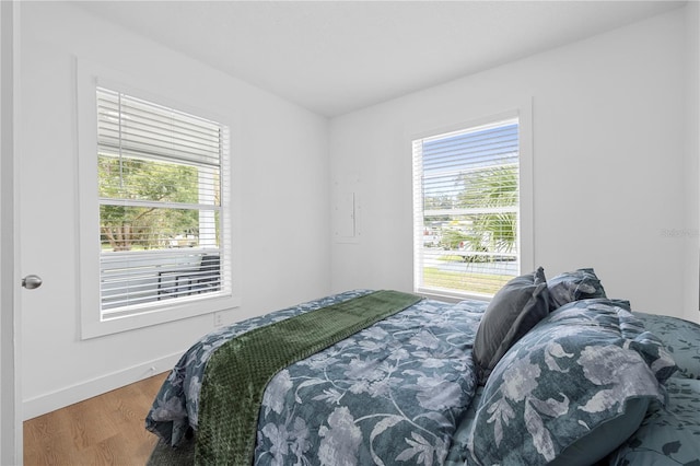 bedroom with multiple windows, baseboards, and wood finished floors