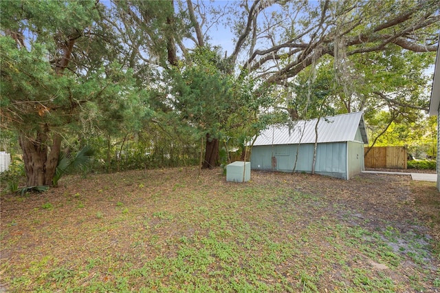 view of yard with an outdoor structure, fence, and an outbuilding