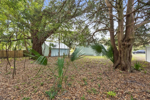 view of yard featuring an outbuilding, fence, and a shed