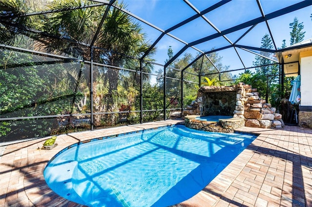 view of pool with a lanai, a patio area, and an in ground hot tub