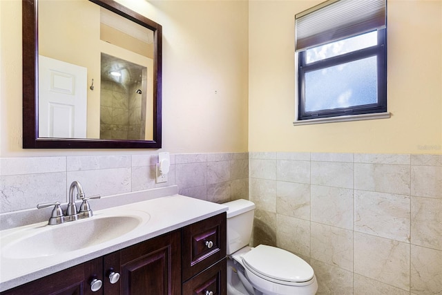 bathroom with vanity, toilet, and tile walls