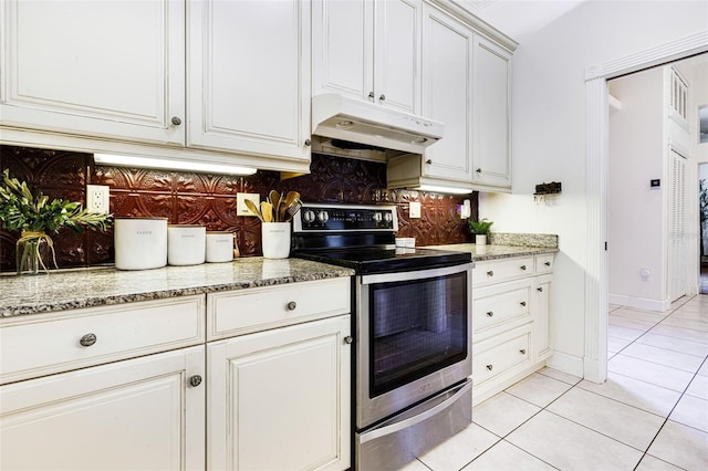 kitchen with light stone countertops, light tile patterned floors, stainless steel electric range, decorative backsplash, and white cabinets