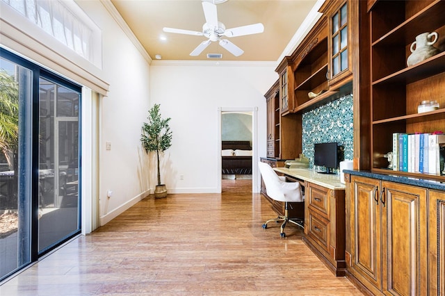 home office with light wood-type flooring, built in desk, ceiling fan, and crown molding