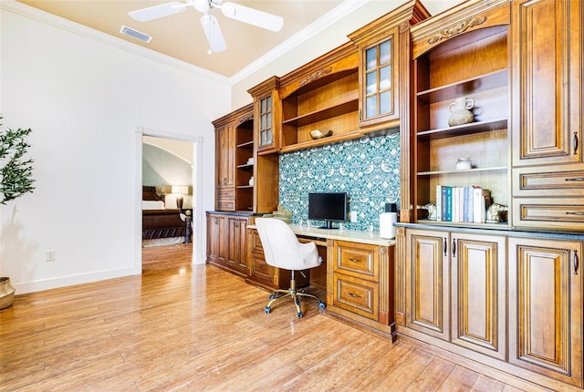 office featuring ceiling fan, ornamental molding, built in desk, and light hardwood / wood-style floors