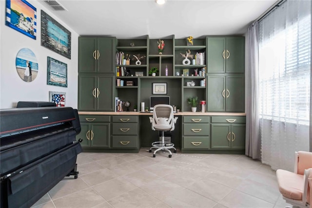 office area featuring light tile patterned floors, visible vents, and built in study area