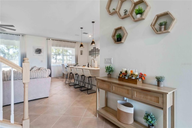 living area with light tile patterned floors and ceiling fan