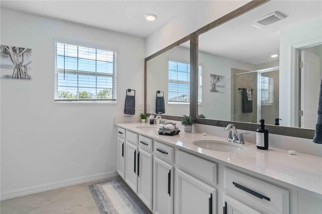 bathroom featuring visible vents, a shower stall, baseboards, double vanity, and a sink