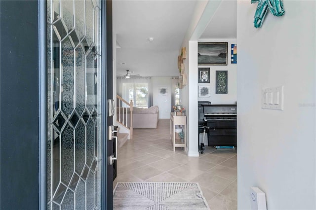 tiled entryway featuring ceiling fan and stairs