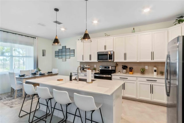 kitchen with a sink, stainless steel appliances, backsplash, and white cabinetry