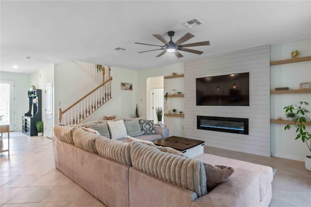 living room with visible vents, a large fireplace, stairway, light tile patterned flooring, and a ceiling fan