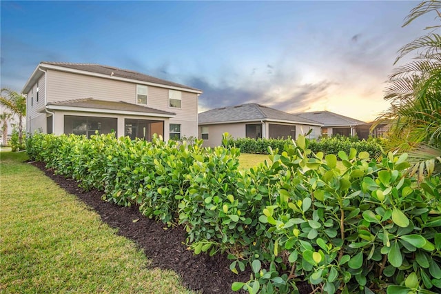 back of property with a yard and a sunroom