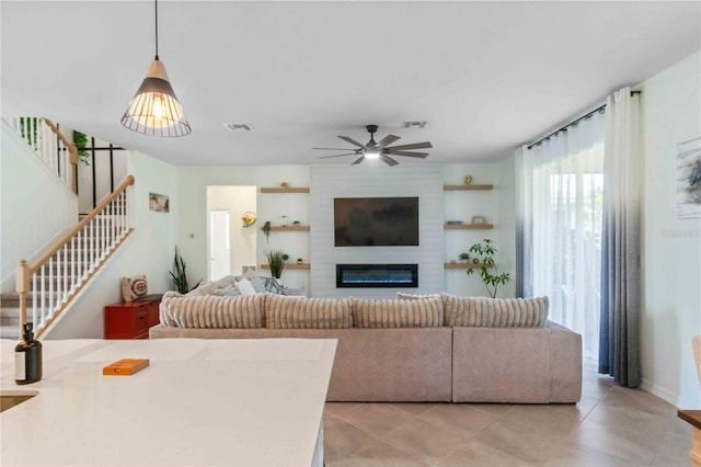 living room featuring stairs, light tile patterned floors, visible vents, and ceiling fan