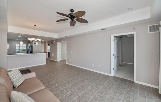 unfurnished living room featuring a raised ceiling and ceiling fan with notable chandelier