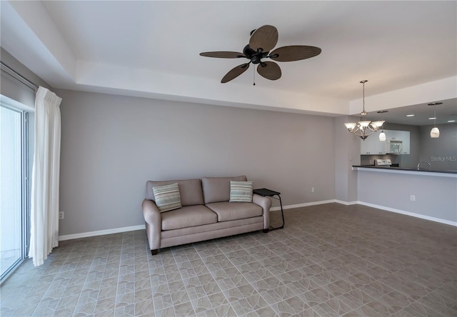 living room with ceiling fan with notable chandelier and sink