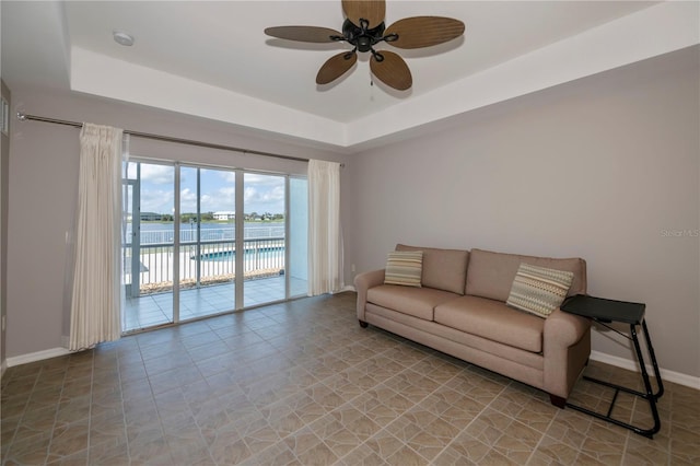 living room with a tray ceiling and ceiling fan