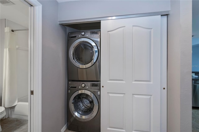 clothes washing area with tile patterned floors and stacked washer / dryer