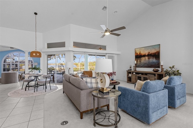 living area featuring plenty of natural light, light tile patterned flooring, visible vents, and high vaulted ceiling