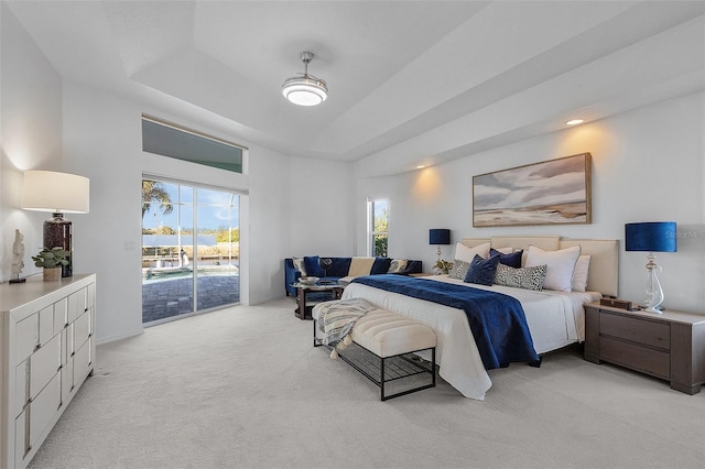 bedroom featuring access to exterior, light carpet, a tray ceiling, and multiple windows