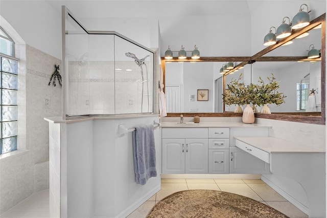 bathroom featuring tile patterned flooring, vanity, and a tile shower