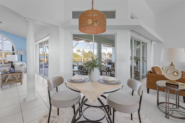 tiled dining area featuring ornate columns, a wealth of natural light, and a towering ceiling