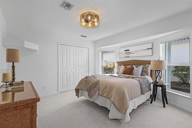 bedroom with a textured ceiling, a closet, light carpet, and multiple windows