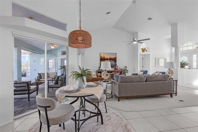 dining room with ceiling fan, light tile patterned floors, high vaulted ceiling, and decorative columns