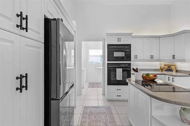 kitchen with light tile patterned floors, white cabinetry, and black appliances