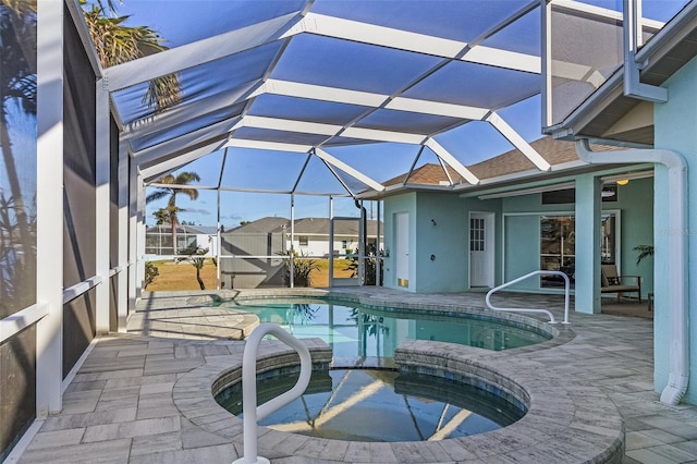 view of swimming pool with glass enclosure, an in ground hot tub, and a patio area