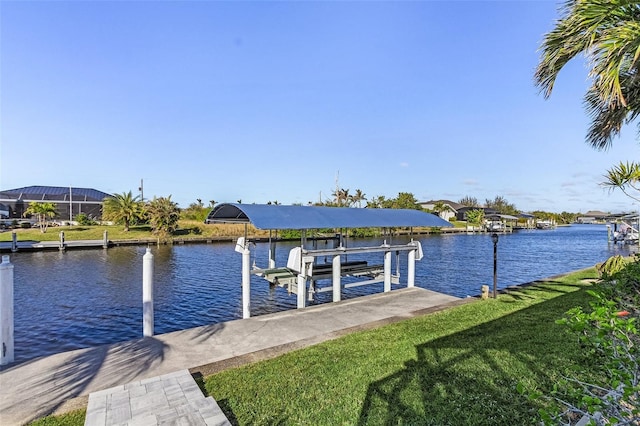 dock area with boat lift, a lawn, and a water view