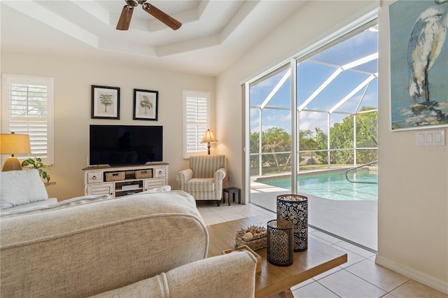 living room featuring a wealth of natural light, a tray ceiling, a sunroom, and light tile patterned floors