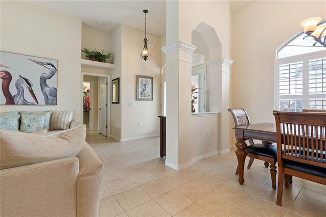 dining room featuring light tile patterned floors, arched walkways, a towering ceiling, baseboards, and decorative columns