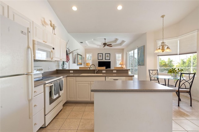 kitchen featuring decorative light fixtures, dark countertops, a sink, white appliances, and a peninsula