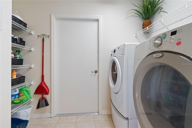 laundry room featuring laundry area, light tile patterned flooring, baseboards, and separate washer and dryer