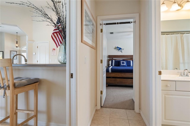 hall featuring light tile patterned floors, arched walkways, light colored carpet, visible vents, and baseboards