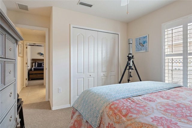 bedroom with light carpet, baseboards, visible vents, and a closet