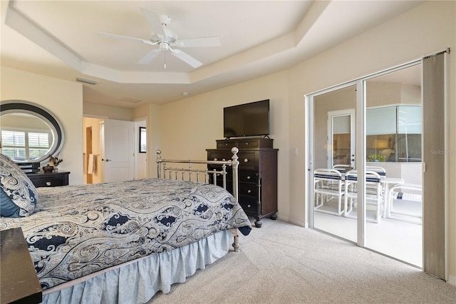 bedroom with a tray ceiling, visible vents, a ceiling fan, light carpet, and access to outside