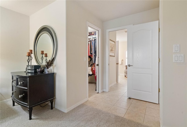 corridor featuring light colored carpet, baseboards, and light tile patterned floors