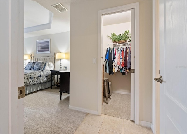 bedroom with light tile patterned floors, visible vents, a spacious closet, light carpet, and baseboards