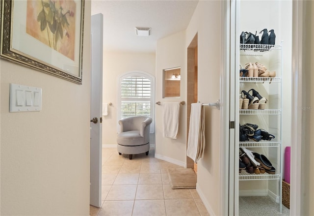 corridor with visible vents, baseboards, and light tile patterned floors