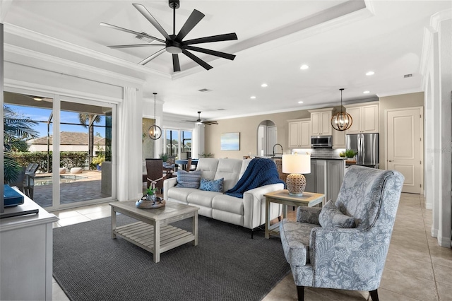 living room with light tile patterned floors, a tray ceiling, ceiling fan, and crown molding