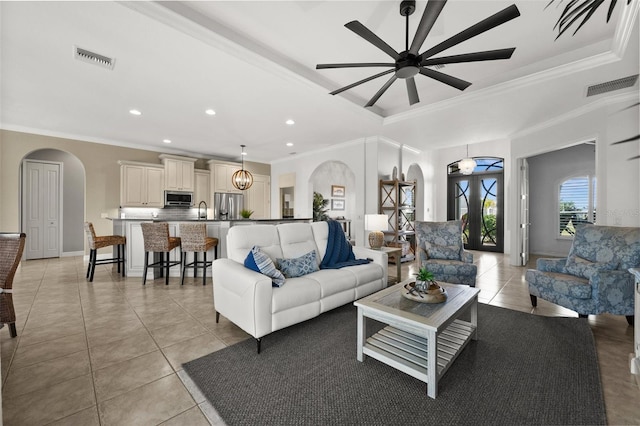 living room with light tile patterned floors, ceiling fan with notable chandelier, and ornamental molding