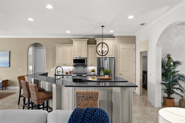 kitchen featuring cream cabinetry, a center island with sink, light tile patterned floors, and stainless steel appliances