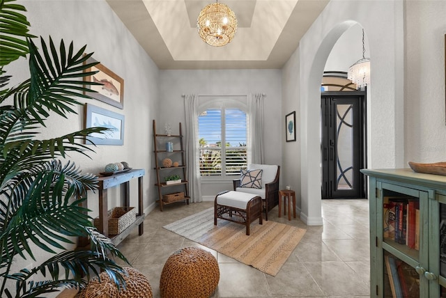 sitting room with a tray ceiling, a notable chandelier, and light tile patterned flooring