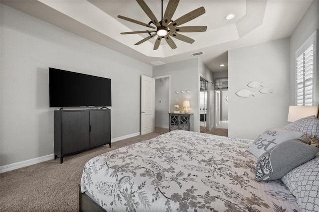 carpeted bedroom featuring a tray ceiling and ceiling fan